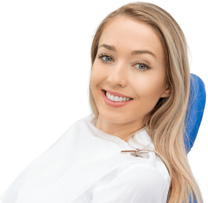 A woman with long hair sits in a dental chair, smiling. She wears a white dental bib.